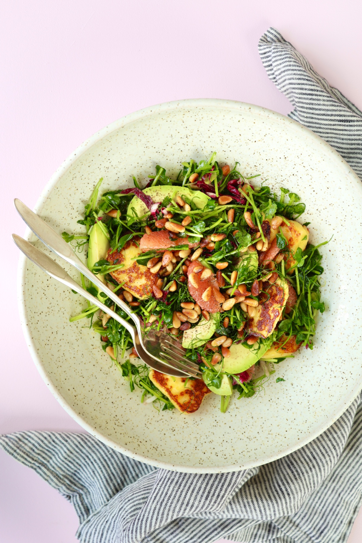 Pea shoot salad with grapefruit, avocado and grilled cheese on a plate