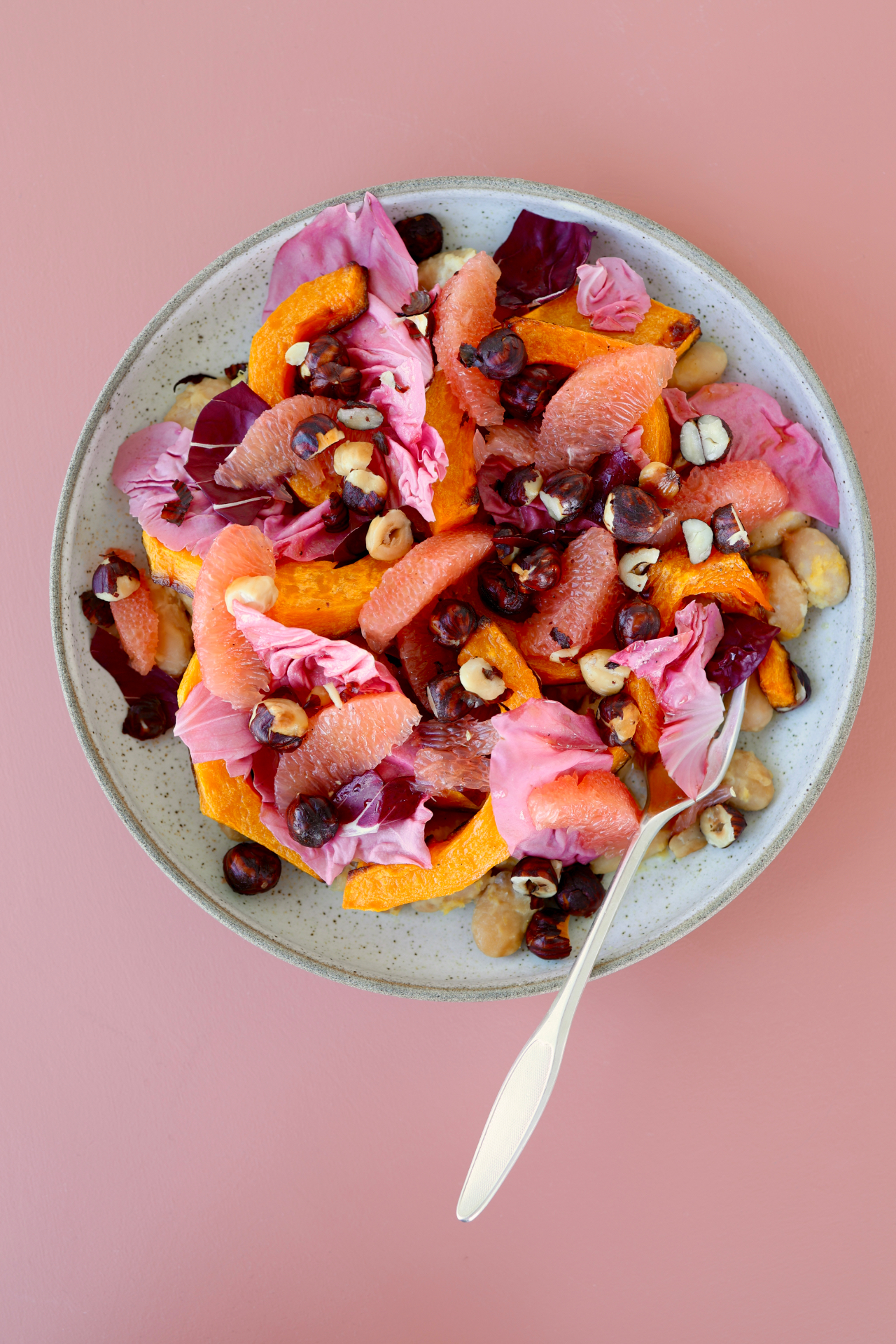 Butter beans with roasted butternut squash, grapefruit segments and hazelnuts on a plate